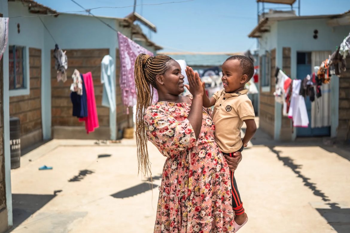 A mother high-fiving a child she's carrying in her arms.